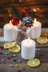 Obraz na płótnie Canvas Christmas decorations, burning candles, candy ,citrus, spruce on a wooden background. New Year's concept. Postcard