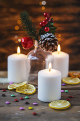 Christmas decorations, burning candles, candy ,citrus, spruce on a wooden background. New Year's concept. Postcard