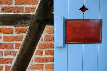 Old  enamel sign, metal sign, information sign, without inscription,on a rustic, light blue painted wooden door