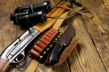 Fototapeta premium Hunting rifle and ammunition lie on wooden background.