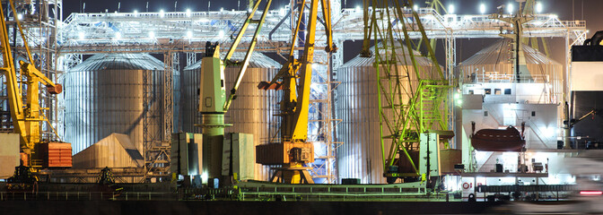 Port grain elevator in night time. Industrial sea trading port bulk cargo zone grain terminal. Panoramic view of the cargo port of Odessa
