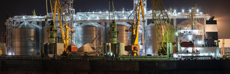Port grain elevator in night time. Industrial sea trading port bulk cargo zone grain terminal....