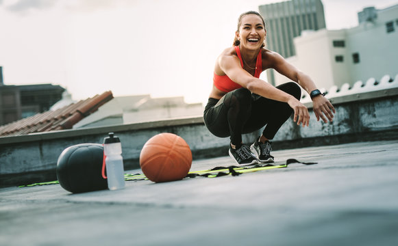 Smiling fitness woman doing sit ups on rooftop