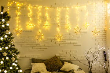 Coziness, comfort, interior and holidays concept - cozy bedroom with bed and christmas garland lights at home