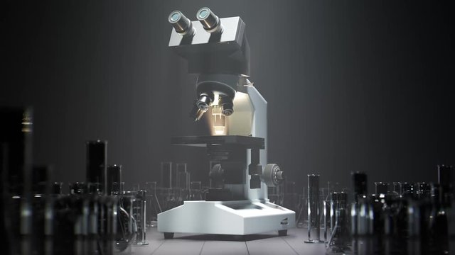 Modern microscope standing beside glassware under a spotlight in a laboratory.