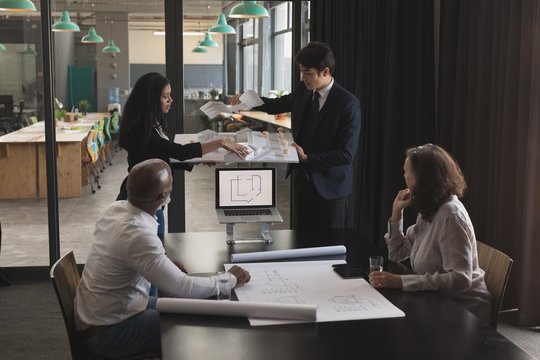 Architects talking over house model in conference room