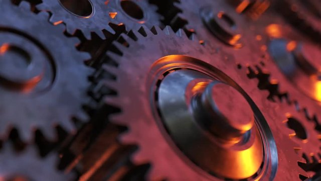 Closeup on slowly rotating dark metallic gears. Clockwork machinery in motion.