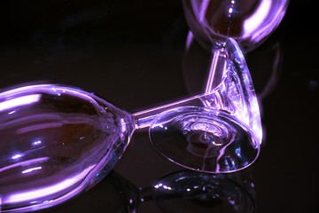 Two wine glasses lying with stems crossed on black background