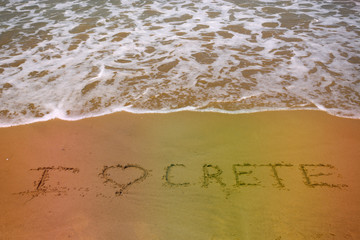 Love Crete words on sand beach texture with sea wave on background. Summer concept