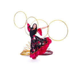 A young,smiling girl in a long skirt dancing with a Hoop.