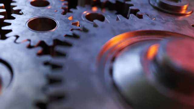 Closeup on slowly rotating dark metallic gears. Clockwork machinery in motion.