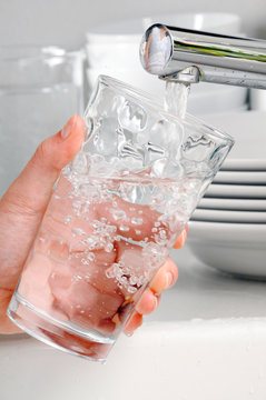 WOMAN FILLING GLASS TUMBLER WITH TAP WATER