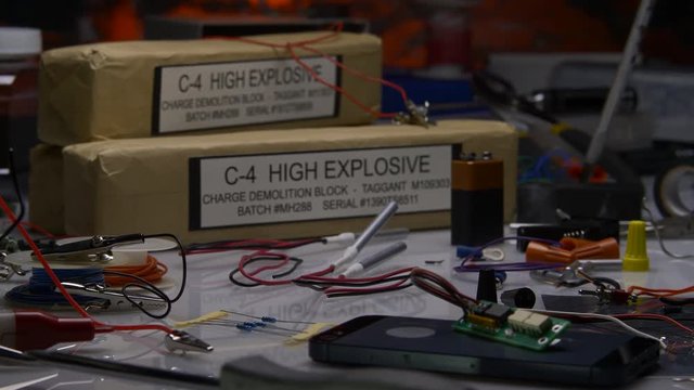 HIGH EXPLOSIVE C4 BOMB UNDER CONSTRUCTION, IN 4K 10 BIT.  ECU SLIDER SHOT OF GLOVED HANDS SOLDERING ELECTRICAL CONNECTIONS.