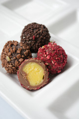 Truffle chocolate collection in white plate. Close up of perfect dessert with creamy filling,  raspberry and chocolate crisps.