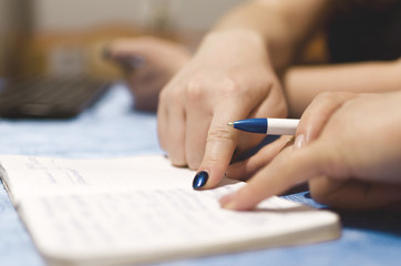 Woman is writing a notes in a notebook and plans daily schedule, close up photo.