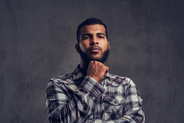 Portrait of a pensive African-American guy with a beard wearing a checkered shirt