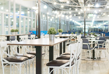 Modern airport lounge with tables and chairs.