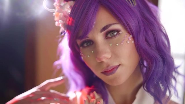 Charming girl dressed as asian anime charachter: purple wig, makeup and pink kimono.