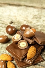 Almonds in chocolate glaze on a old wooden table. Unhealthy food. Risk of obesity and diabetes. Sweet nuts. Almond chocolate dragees