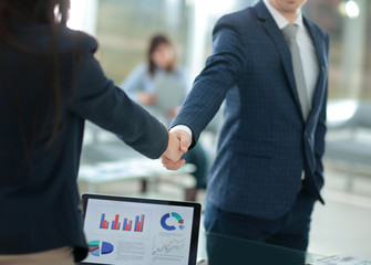 handshake financial partners, on the desktop background, with the financial schedule