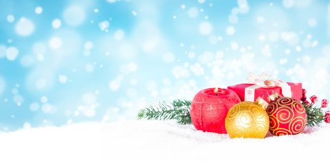 Red and golden decorations in snow on blue blurred background.