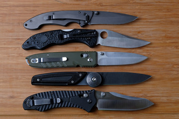 Folding knives on a wooden background.