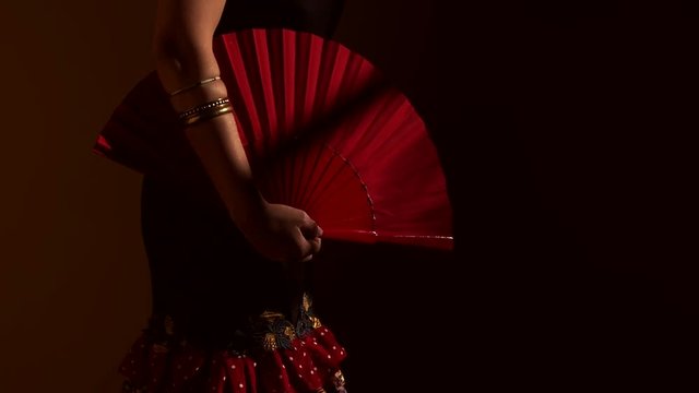 Close up woman showing one red fan open and close in traditional spanish dress