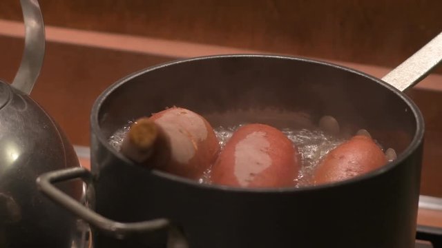 Sweet potatoes in a black pot of boiling water on a home stove top.