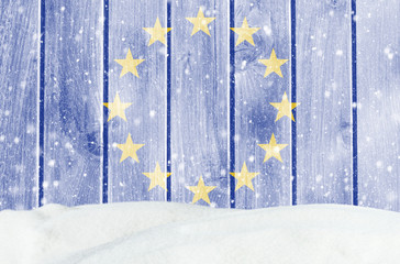 Christmas winter background with wooden wall, falling snow, snowdrift and European union flag