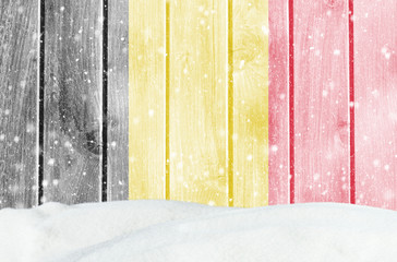 Christmas winter background with wooden wall, falling snow, snowdrift and Belgian flag