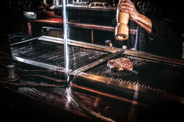 Master chef wearing uniform cooking delicious beef steak on a kitchen in a restaurant