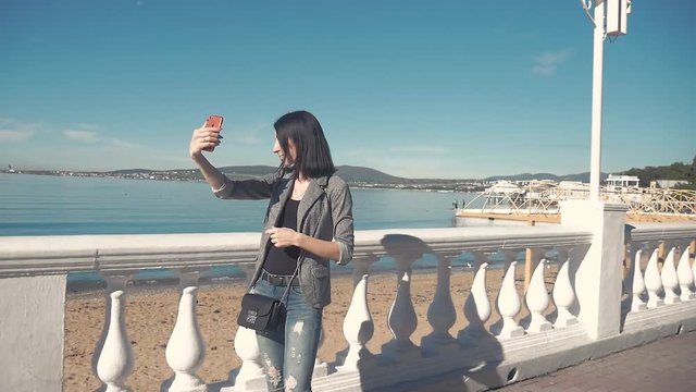 Back view of a woman taking photograph with a smart phone camera at the horizon on the beach.Young girl taking photos of blue sea on mobile phone.
