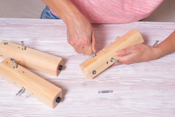 Woman hands assamble wooden furniture