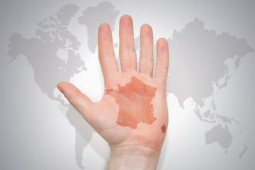 hand with map of france on the gray world map background.