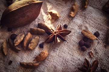 Close-up photo. Black peppercorn, beans, cinnamon, pecan on linen fabric.