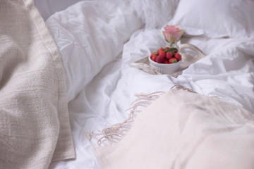 Fototapeta na wymiar Strawberries and roses in bed in the morning. Romance and tenderness at home. Copy space.