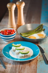 brunch of curd cheese sandwiches with avocado, tomatoes, boild green asparagus and fried eggs on the plate