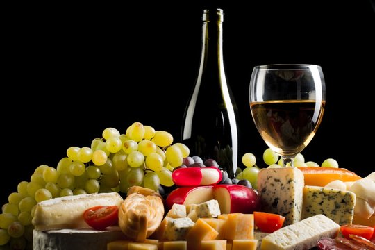 Wine Bottle, Wine Glass, Cheeses and Grapes on the Black