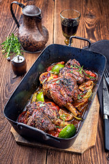 Traditional barbecue leg of lamb with lemon and tomatoes as closeup in an old skillet