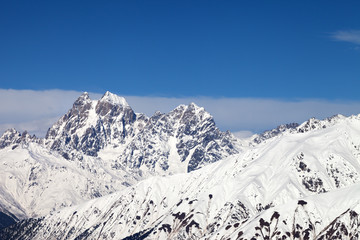 Snowy mountains and blue sky with clouds at sunny winter day