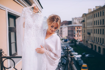 Morning of the bride. A happy bride is dancing with a dress on the hotel's balcony.