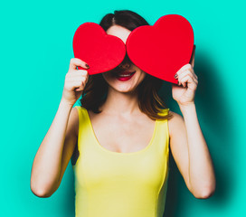 portrait of beautiful young woman with heart shaped gifts on the wonderful blue studio background