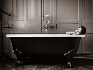 photo of beautiful young woman lying in bath and resting . Image in black and white color style
