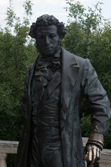 Pushkin monument with a shiny hand on the background of the forest. Pushkin in on belt. for Pushkin the railing of the embankment