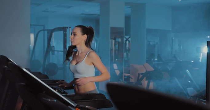 In the gym a beautiful girl runs. Treadmill. Close-up