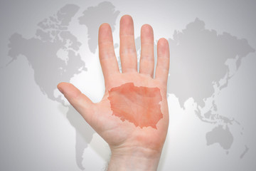 hand with map of poland on the gray world map background.