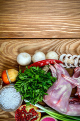 Rabbit rabbit meat with vegetables on wooden table background. Homemade traditional cuisine recipe. Flat view, overhead. vertical image. space for text