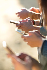 Young group of friends chatting with their smartphones in the street.