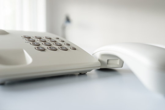 Closeup of white landline telephone with handset off the hook