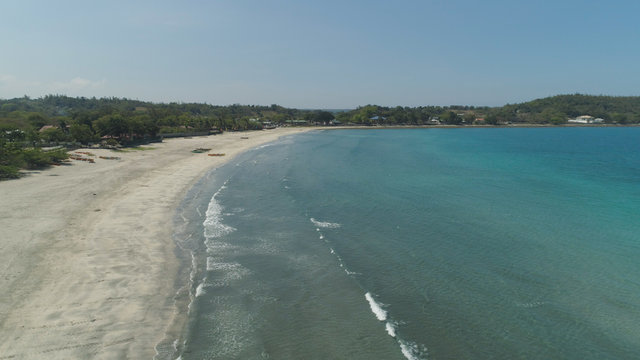 Beautiful tropical beach Cabugao with white sand and palm trees in the Philippines, Luzon. Aerial view of coast with beach and turquoise water.